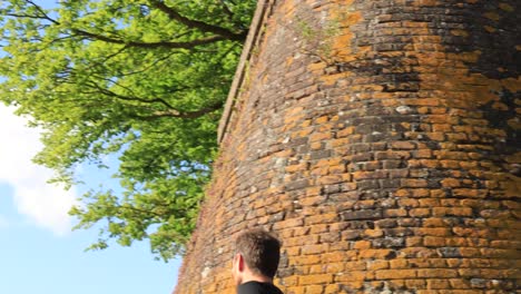 Approaching-male-trail-runner-coming-towards-the-camera-turning-passed-historic-defense-wall-with-city-countenance-boulevard-in-the-back-against-a-blue-sky-with-clouds