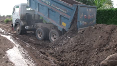 A-slow-motion-scene-in-which-a-large-loader-truck-unloads-soil-from-its-truck,-preparing-to-avoid-a-road-block-due-to-heavy-rain