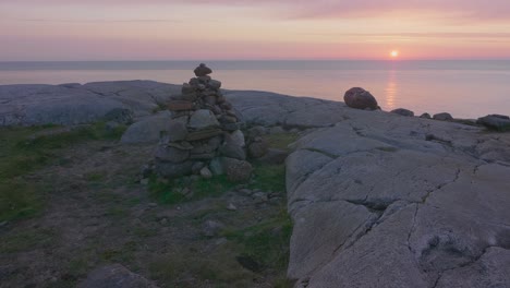 Rock-stack-balancing-on-the-top-of-a-cliff-overlooking-the-calm-ocean-with-a-beautiful-golden-sunset-in-the-Scottish-highlands