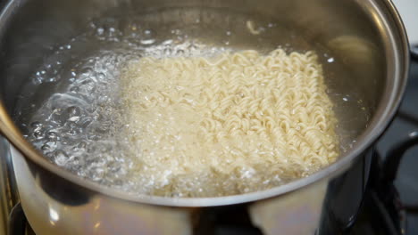 Adding-a-brick-of-ramen-noodle-to-a-pot-of-boiling-water