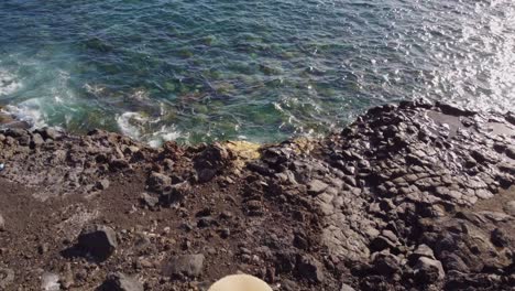 Elegant-female-enjoys-rocky-coast-of-Canary-islands,-back-above-view