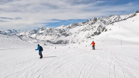 Follow-shot-of-male-snowboarder-descent-on-ski-slope-with-mountain-range-view,-Cervinia