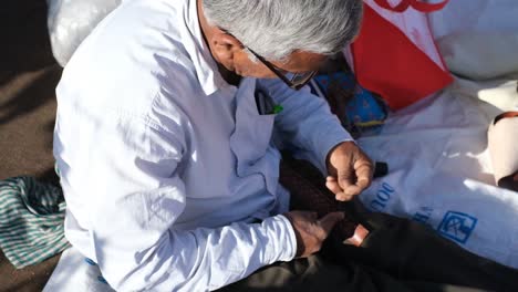 An-Indian-cobbler-on-a-street-road-sewing-a-leather-belt-with-both-his-hands