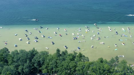 Aerial-shot-from-shore-of-Boats-and-People-in-shallow-crystal-clear-Glacial-Lake-water-on-Sunny-Summer-Day-Higgins-Lake-Michigan