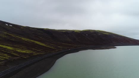 Distant-Aerial-Follow-Behind-Car-Driving-through-the-valley-of-the-Kaldidalur-Mountain-and-Lake-Sandkluftavatn