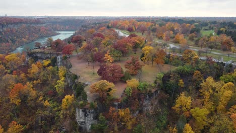 Stunning-cliffs-with-fall-colored-trees-line-park-overlooking-river