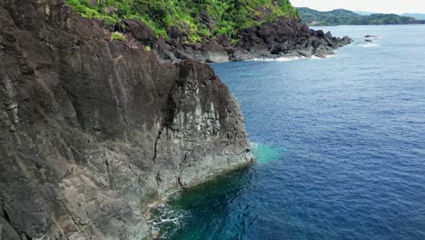Cinematic-aerial-drone-shot-of-jagged-coastline-rocks-by-tropical-island-cove-in-the-Philippines