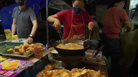 Street-Vendor-Prepares-Local-Fried-Food,-Evening-Street-Food-Market,-Kuala-Lumpur,-Malaysia