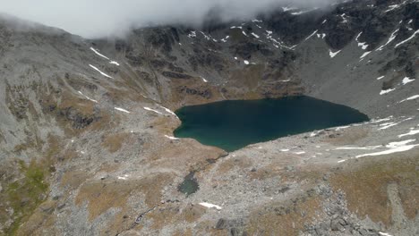 Beautiful-New-Zealand-high-mountain-landscape-of-Lake-Alta-surrounded-by-foggy-peaks,-drone-shot