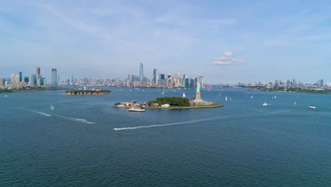 Toma-Aérea-De-Barcos-Frente-A-La-Estatua-De-La-Libertad-Y-El-Horizonte-De-La-Ciudad-De-Nueva-York