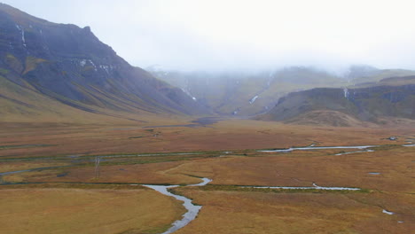 Drone-view-of-overcast-skies,-mountains,-barren-ground,-valleys-and-streams-in-Icelandn-Kirkjufell-Mountain-near-Grundarfjordour