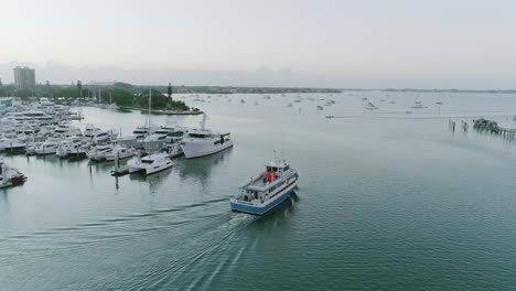 Toma-Aérea-En-órbita-Acercándose-A-Un-Barco-Pesquero-En-La-Bahía-De-Sarasota-Saliendo-Del-Puerto-Deportivo-Durante-El-Amanecer.