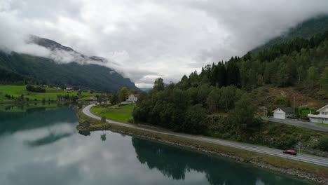 Aerial-Forward-Dolly-Shot-of-Car-Driving-through-the-Beautiful-Landscaping-Next-to-the-Svortesvada-Fjord-in-Stryn