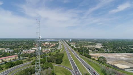 Panning-Shot-of-a-Radio-Tower-Next-to-Highway-in-Florida-on-a-Sunny-Day