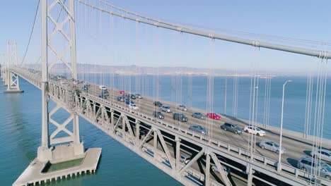 Antena-De-Tráfico-Pesado-En-El-Puente-De-La-Bahía-De-Oakland-Disminuyendo-La-Altitud-Revelando-El-Cielo-Azul