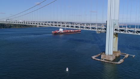 Aerial-Forward-Crane-Towards-Freighter-Passing-Under-Bridge-in-New-York-City