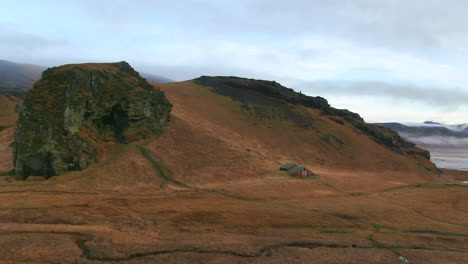 Panoramic-view-of-mountains,-ocean-and-abandoned-barns-in-a-valley-on-an-overcast-day-in-Iceland