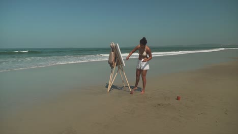Totale-Aufnahme-Einer-Jungen-Künstlerin,-Die-An-Einem-Sonnigen-Strand-Malt,-Eine-Elegante-Frau-Malt-Künstlerischen-Ausdruck-Im-Freien