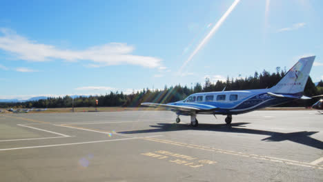 A-shot-of-a-private-jet-charter-and-helicopter-standing-on-a-small-airport-side-by-side-on-a-sunny-day-in-British-Columbia,-Canada