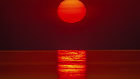 Close-up-of-red-sun-rising-from-the-sea-horizon,-Timelapse