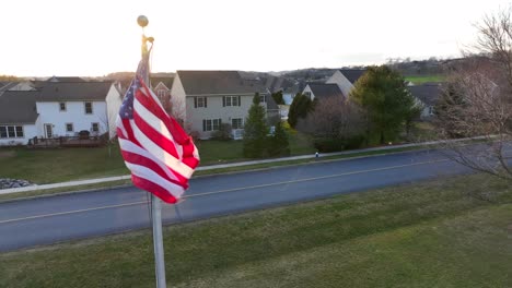 American-flag-waving-in-front-of-neighborhood-in-USA-during-sunset