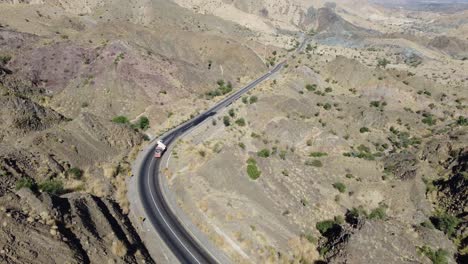 Luftdrohnenaufnahme-In-Vorwärtsbewegung-über-Autos-Und-Lastwagen,-Die-An-Einem-Sonnigen-Tag-Auf-Einer-Kurvenreichen-RCD-Straße-Durch-Belutschistan-Fahren