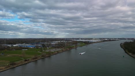 Aerial-view-of-canal-with-moving-vessels-in-The-Netherlands-during-cloudy-day
