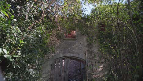 Verlassener-Burgverfall-In-Südfrankreich-Mit-Einer-Kaputten-Holztür-Und-Natur,-Die-Das-Gesamte-Gebäude-überwuchert