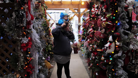 A-woman-taking-a-toddler-on-her-shoulders-and-checking-out-the-stuff-for-sale-in-a-market-for-Christmas-in-BC,-Canada