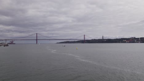 Drone-flyover-Tagus-river-toward-April-25th-Bridge-with-seagulls-flying,-Lisbon