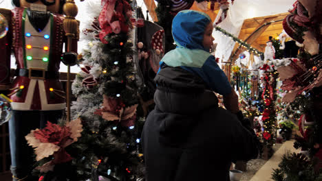 A-woman-taking-a-toddler-on-her-shoulders-and-checking-out-the-stuff-for-sale-in-a-market-for-Christmas-in-BC,-Canada