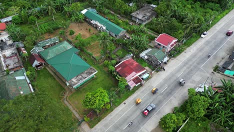 Vista-Aérea-Del-Barrio-Rural-Filipino-Con-Palmeras,-Casas-En-Ruinas-Y-Carretera-Transitada-En-Catanduanes,-Filipinas