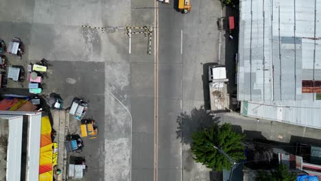 Birdseye-Top-Down-View-of-Tricycles-and-Commuters-traveling-around-Southeast-Asian-Public-Market-area-with-damaged-streets-and-parked-vehicles-in-background
