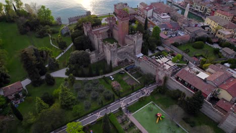 Aerial-tilt-up-view-revealing-a-medieval-castle-in-Italian-village-of-lake-Garda
