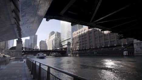 Wide-angle-shot-of-water-taxi-boat-driving-under-the-famous-bridge-of-Chicago