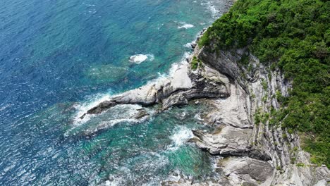 Majestätische-Luftaufnahme-Der-Südostasiatischen-Küste-Mit-Atemberaubenden-Türkisfarbenen-Meereswellen-Und-Felsformationen-Aus-Liegenden-Falten