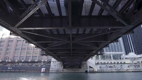 Cars-driving-over-famous-bridge-in-Chicago,-yellow-Watertaxi-rides-underneath