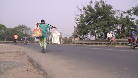 A-person-walking-on-the-road-with-a-load-on-his-shoulder