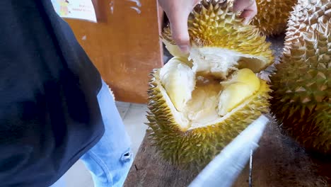 Opening-durian-fruit-with-knife,-close-up-view