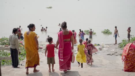 Tourists-and-pilgrims-bathing-and-swimming-in-river-bank-of-Ganga-in-India-to-wash-off-their-sins-in-Summer,-Rani-Rashmoni-ghat,-slow-motion
