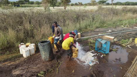Borehole-well-supplying-local-village-with-drinkable-water,-African-kids-collect-clean-water