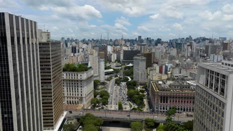 Aerial-overview-of-traffic-on-a-highway-in-middle-of-buildings-in-sunny-Sao-Paulo,-Brazil