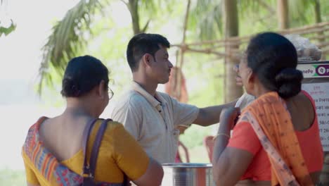 Two-Indian-women-eating-spicy-Indian-street-food-Phuchka-or-Golgappe-from-a-stall,-outdoor,-slow-motion