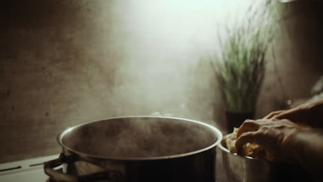 Chef-puts-fresh-fresh-cauliflower-into-pot-boiling-soup,-hand-close-up