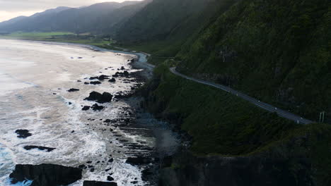 Stunning-aerial-view-of-road-at-cliff-edge-in-Ruatapu,-New-Zealand,-aerial