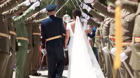 Mann-Und-Frau-Gehen-Bei-Einer-Hochzeit-Mit-Erhobenem-Schwert-Zwischen-Militärmännern-Umher