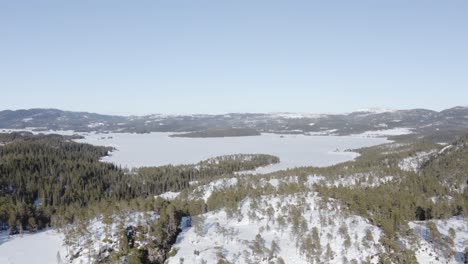 Panoramic-Aerial-View-Of-Snow-Covered-Forest-And-Mountain-Lakes-During-Winter