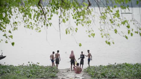 Poor-unemployed-Indian-men-bathing-in-river-bank-of-Ganga-to-wash-off-their-sins-in-Summer,-Rani-Rashmoni-ghat,-slow-motion