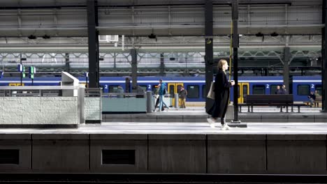 People-walk-on-train-platforms-at-Amsterdam-Central-Station,-static