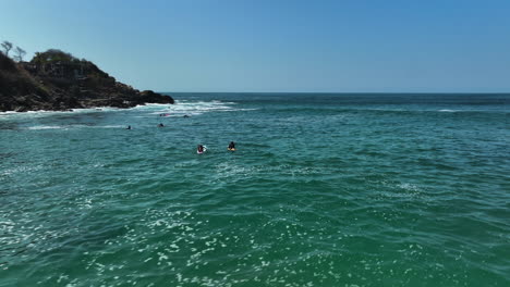 Aerial-view-around-SUP-paddlers-at-the-Playa-Carrizalillo-beach-in-sunny-Puerto-Escondido,-Mexico